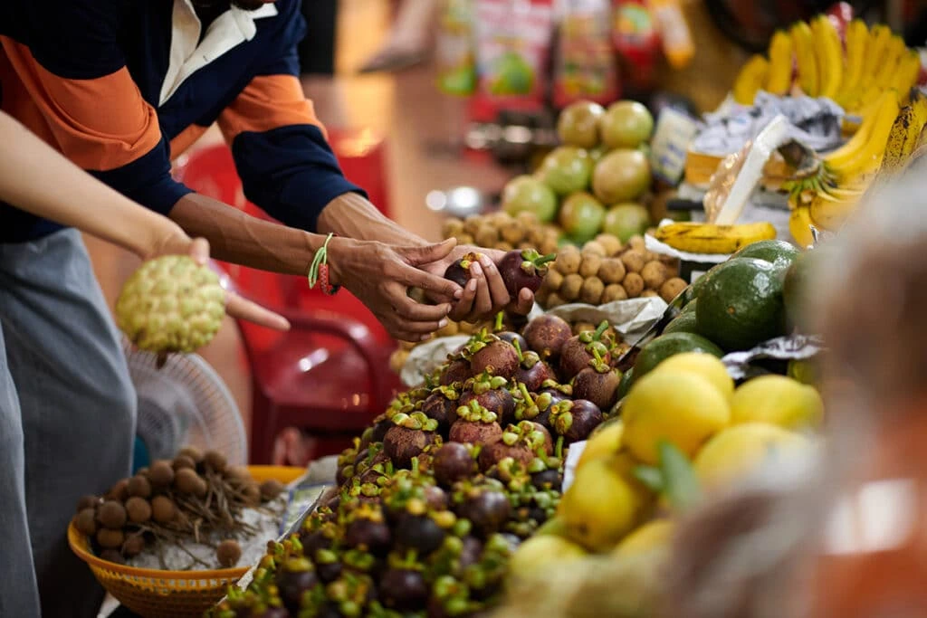 People choosing exotic fruits at a market stall